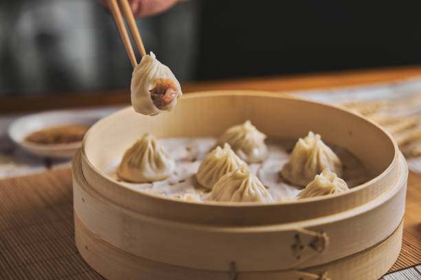 Hand taking  Xiaolongbao with wooden chopsticks.