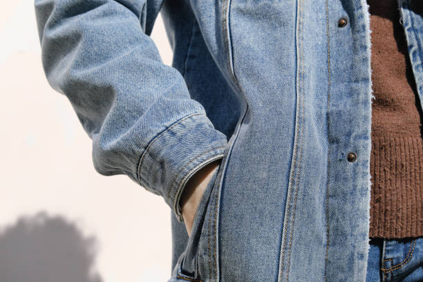 la persona está sosteniendo la mano en el bolsillo de la chaqueta de mezclilla - manos en los bolsillos fotografías e imágenes de stock