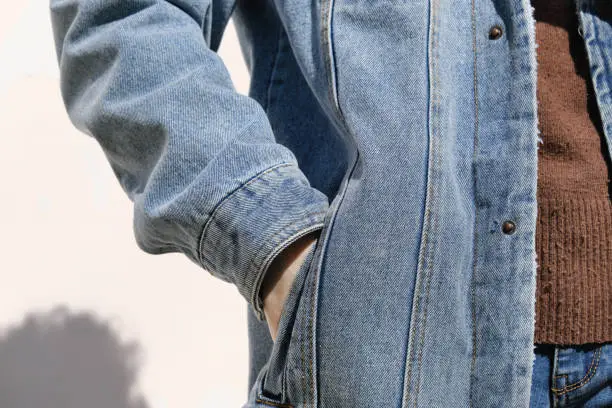 Photo of Person is holding hand in denim jacket's pocket