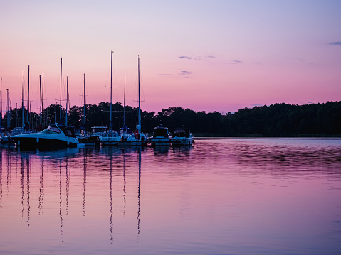 moored sailing yachts on a jetty with reflection in the water at beautiful pink dusk