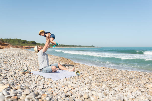 istock Father holding her little daugther up on a mediterranean beach. 1394381725