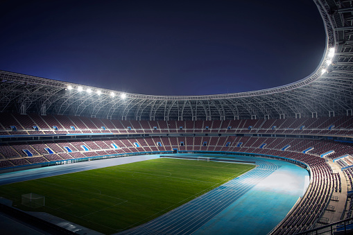 View of empty sports stadium at night with spotlights illuminating field, digitally generated image