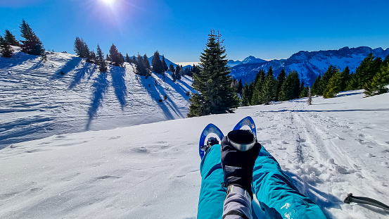 Active woman in snow shoes having a tea break with scenic view on snow capped mountain peaks of Karawanks in Carinthia, Austria. Ski touring. Sunny winter day. Freedom. Winter wonderland, Hochobir.