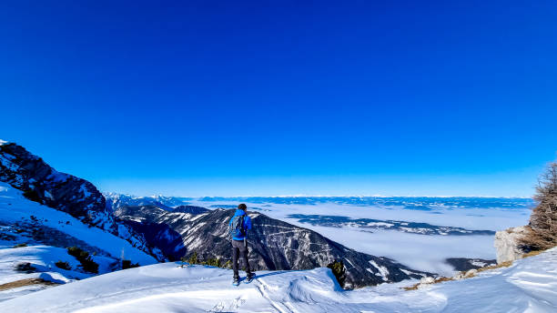 hochobir - homme sur un sentier de randonnée enneigé avec panoramique de hochobir à karawanks en carinthie, alpes autrichiennes. raquette à neige - apres ski winter hiking ski photos et images de collection