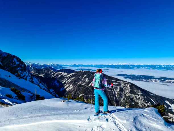 hochobir - femme sur un sentier de randonnée enneigé avec panoramique de hochobir à karawanks en carinthie, alpes autrichiennes. raquette à neige - apres ski winter hiking ski photos et images de collection