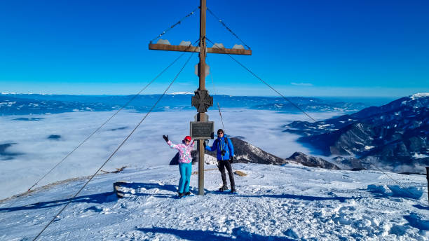 hochobir - couple profitant de la vue panoramique en hiver depuis la croix sommitale de hochobir dans les karawanks en carinthie, alpes autrichiennes - apres ski winter hiking ski photos et images de collection