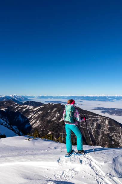 hochobir - mujer en una ruta de senderismo cubierta de nieve con panorámica desde hochobir en karawanks en carintia, alpes austríacos. raqueta de nieve - apres ski ski snow mountain fotografías e imágenes de stock