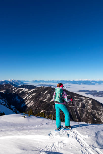 hochobir - femme sur un sentier de randonnée enneigé avec panoramique de hochobir à karawanks en carinthie, alpes autrichiennes. raquette à neige - apres ski winter hiking ski photos et images de collection