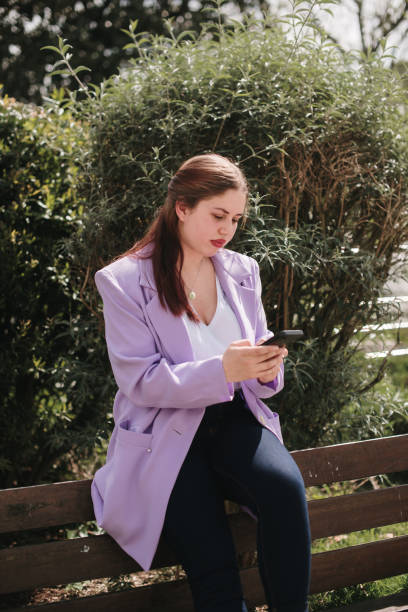 istock Young woman on a bench using a smart phone 1394386264