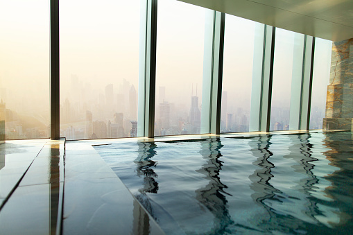 View from luxury infinity pool with glass wall windows to urban city