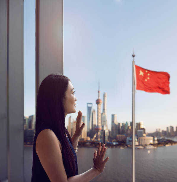 mujer china mirando con orgullo el paisaje urbano de shanghai y la bandera china, china - china shanghai business people fotografías e imágenes de stock