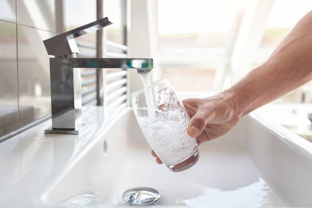 Filling up a glass with drinking water from bathroom tap stock photo