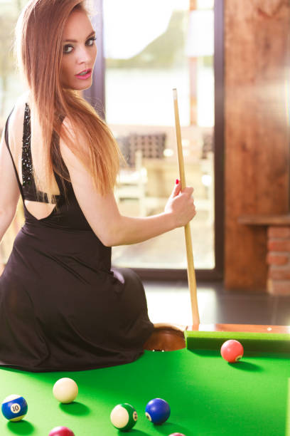 Fashion and fun concept. Young seductive girl posing by billiard pool. Sexy fashionable woman spending time on recreation.