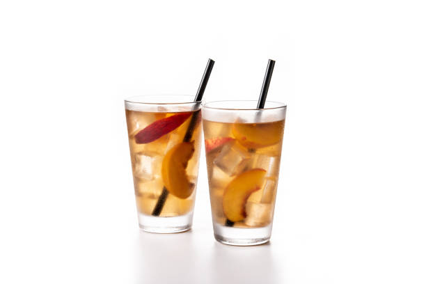Glass of peach tea with ice cubes isolated on white background