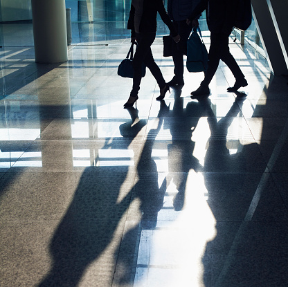 Silhouette of passengers walking through airport terminal with luggage