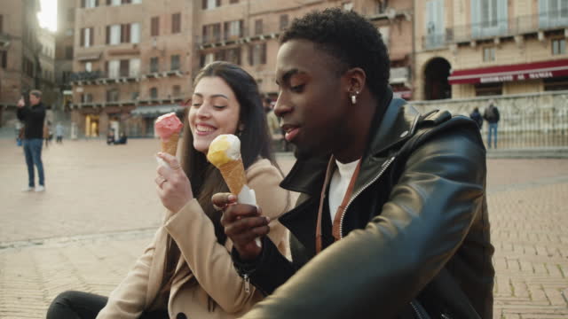 Young adult couple eating an ice-cream in Siena at sunset