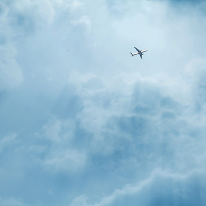 Airplane flying to destination above in dramatic clouds with sun
