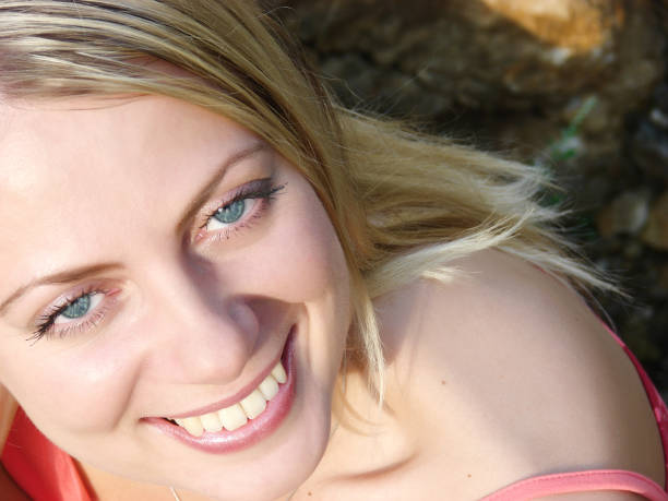 Close-up of a woman's face. Naturally beautiful female with long blond hair and blue eyes looking upwards.