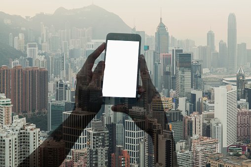 Silhouette of hands holding smartphone with Hong Kong cityscape, China