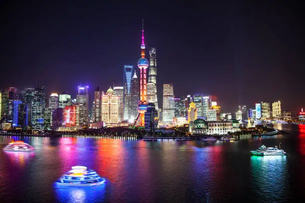 Shanghai's Pudong District's skyscrapers at night with dinner cruise party boats, Oriental Pearl Tower, Shanghai World Financial Center, Shanghai Tower, and Jin Mao Tower, Huangpu River