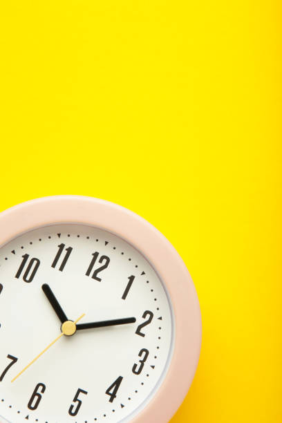 istock Pink clock on yellow background. Top view. 1394393204