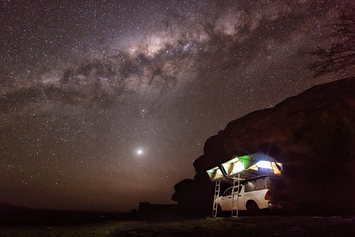 Typical camping in Namibia, Africa: on the roof of the offroad vehicle are two tents for four persons. Under a fantastic starry sky with the milky way.