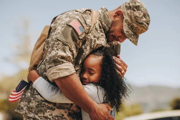 Emotional soldier saying his goodbye to his daughter before going to war. Patriotic serviceman embracing his child before leaving to go serve his country in the military.