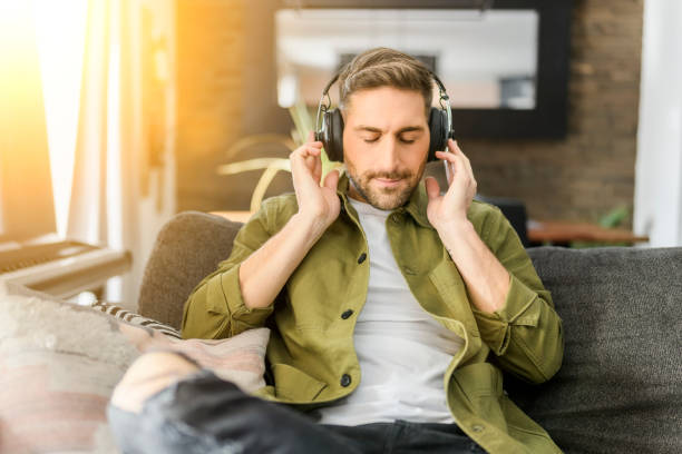 istock Handsome guy wearing headphones enjoys music sit on the comfortable sofa. 1394397614