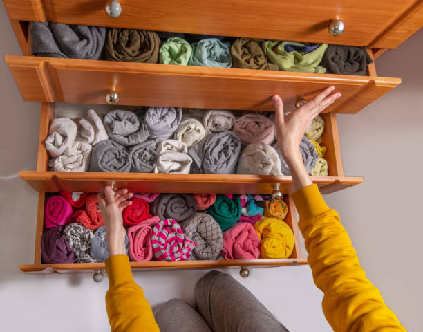 istock Cleaning and sorting clothes in the wardrobe Japanese method. Open chest drawers with  vertical storaged twisting clothes. View from above. 1394398127