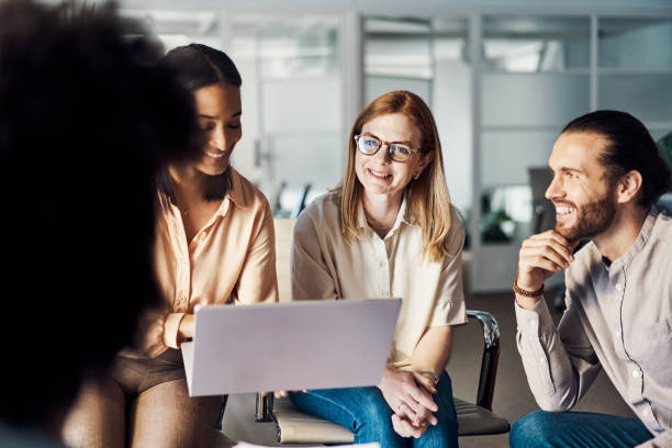 istock Group of businesspeople smiling while using a laptop together at work 1394398851