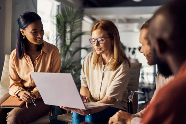 istock Group of four businesspeople using a laptop together at work 1394399164