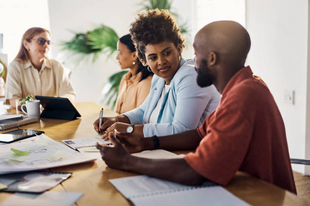 istock Businesspeople talking writing ideas sitting at a table at work 1394400281