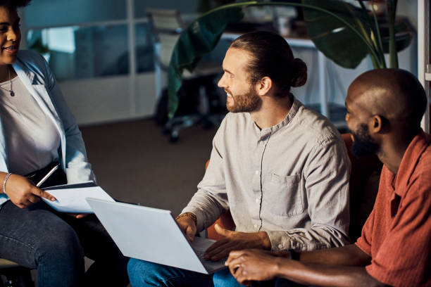 istock Young caucasian businessman using a laptop while in a meeting with coworkers at work 1394400352