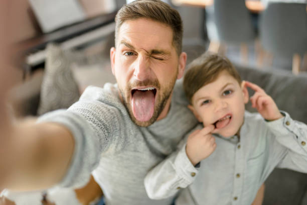 istock Father and son spending time together on sofa taking selfies and making grimaces 1394401806