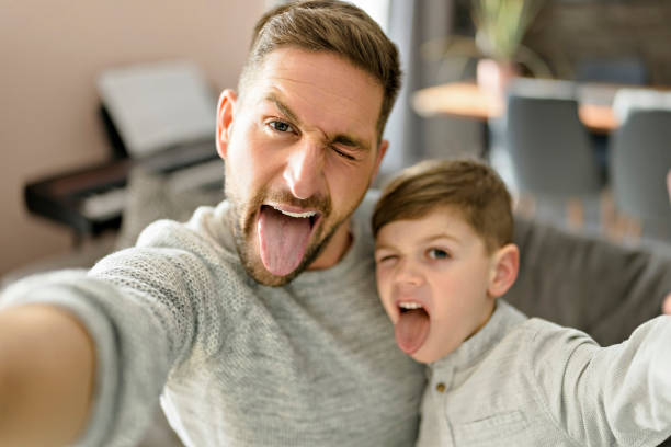 istock Father and son spending time together on sofa taking selfies and making grimaces 1394401825
