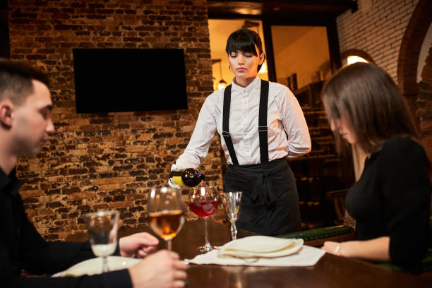 istock The waiter in uniform pours visitors wine in restaurant 1394405231