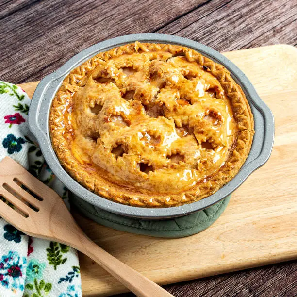 Freshly cooked apple pie sits in a rustic setting.