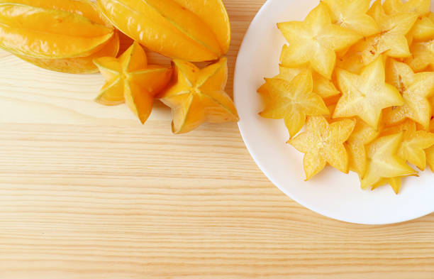 Heap of Fresh Ripe Starfruit with a Plate of Mouthwatering Juicy Slices on Wooden Background Heap of Fresh Ripe Starfruit with a Plate of Mouthwatering Juicy Slices on Wooden Background starfruit stock pictures, royalty-free photos & images