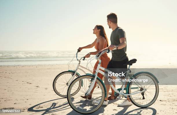 Two People Young Caucasian Couple Enjoying Riding Bicycles On Holiday At The Beach Stock Photo - Download Image Now