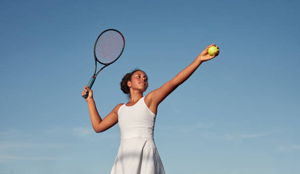 sportiva nera che gioca a tennis contro il cielo blu - termine sportivo foto e immagini stock