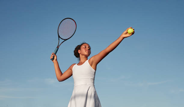 чернокожая спортсменка играет в теннис на фоне голубого неба - tennis uniform стоковые фото и изображения