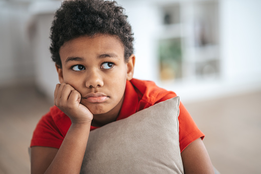 Upset. A boy with a pillow in hands looking upset