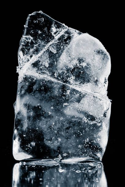 istock Crystal clear natural ice block in cold blue tones on a black reflective surface. 1394413755
