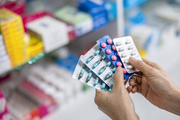 istock capsule in the pharmacist hand and medicine shelf background 1394414668
