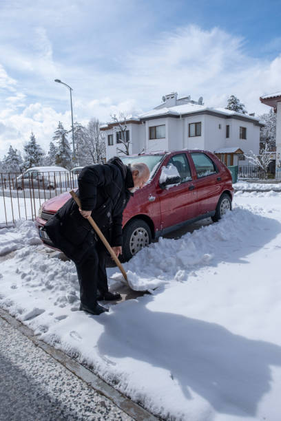 istock old retired man clearing snow on and around his car. 1394414870