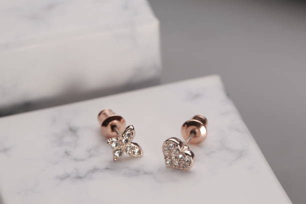A Set of Diamond Earrings on Marble A set of diamond earrings in a butterfly and heart shape on a marble pattern, shot in the studio. diamond earring stock pictures, royalty-free photos & images
