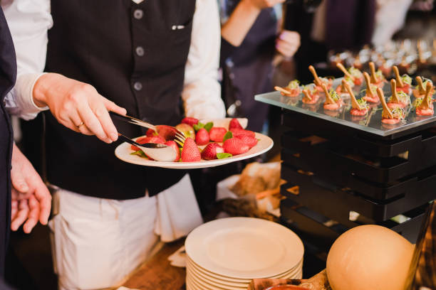 Waiter serving strawberry near catering banquet table at wedding reception. Restaurant presentation, molecular gastronomy, food consumption, party concept. food service occupation food and drink industry party buffet stock pictures, royalty-free photos & images