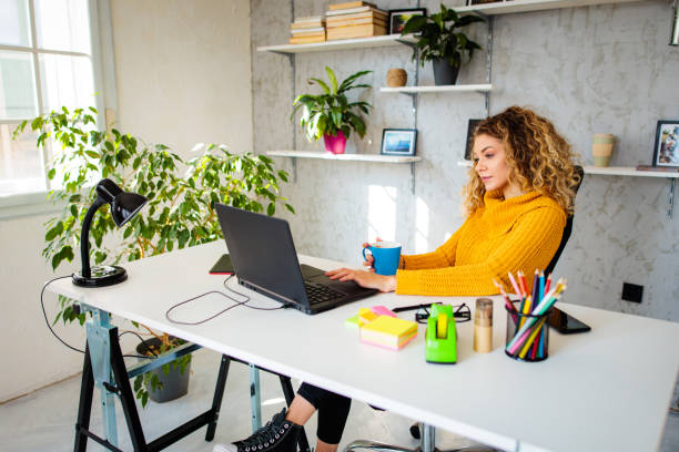 istock Young woman enjoys coffee while working on laptop 1394416307