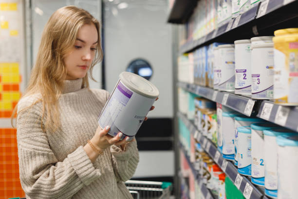 Woman buys infant milk formula at supermarket, portrait of young mother in shop mall stock photo