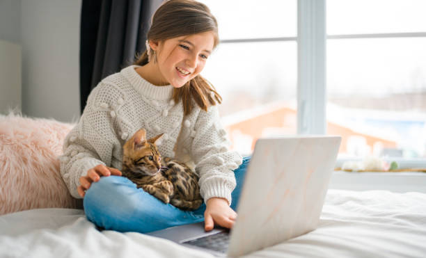 istock bengal cat with Child on computers sit bed at home 1394417446
